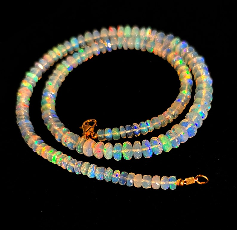 May include: A delicate necklace made of iridescent opal beads. The necklace is strung on a gold chain and features a simple clasp.