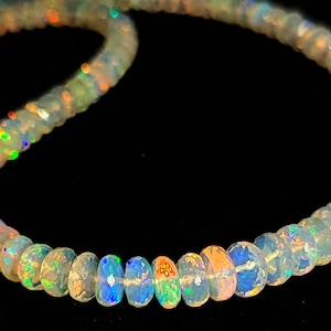 May include: A strand of iridescent opal beads, each bead is a light milky white with flashes of rainbow color.