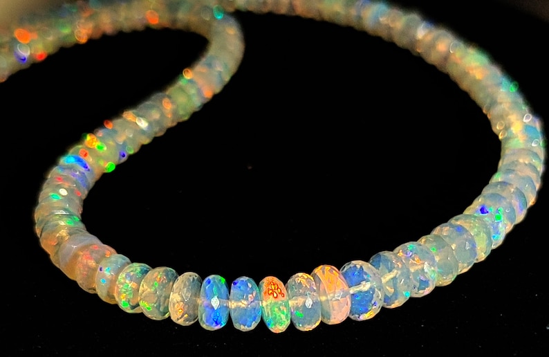 May include: A strand of iridescent opal beads, each bead is a light milky white with flashes of rainbow color.