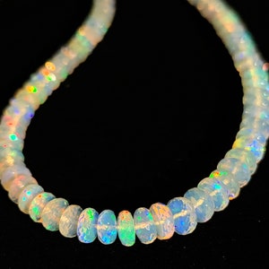 May include: A white opal bead necklace with iridescent rainbow colors. The beads are round and have a smooth, polished finish.