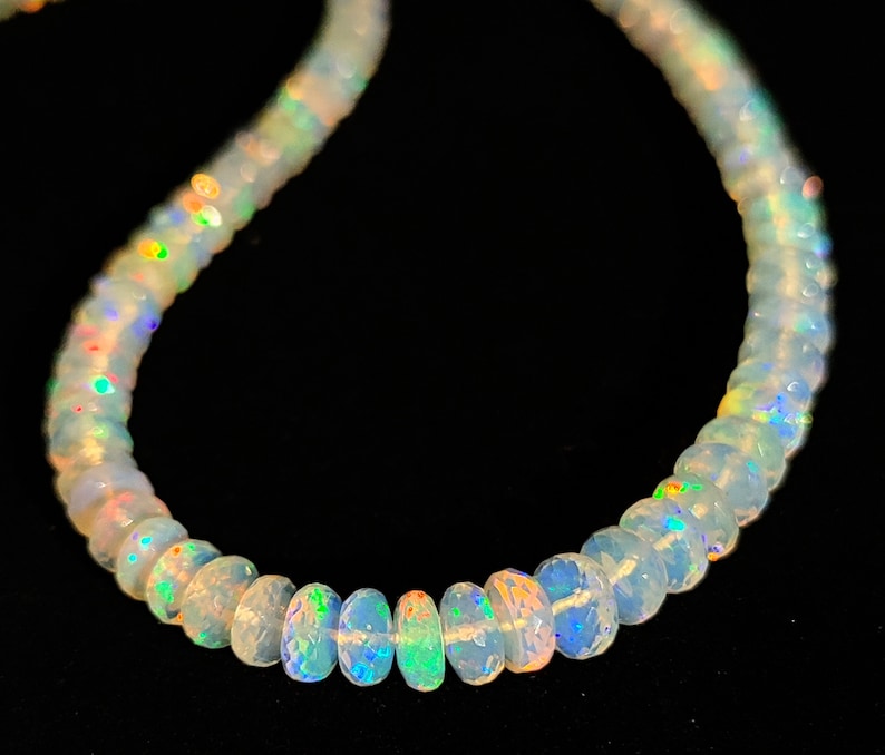 May include: A white opal bead necklace with iridescent rainbow colors. The beads are round and have a smooth, polished finish.