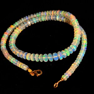 May include: A delicate necklace made of iridescent opal beads with a gold clasp. The necklace is layered and has a subtle shimmer.