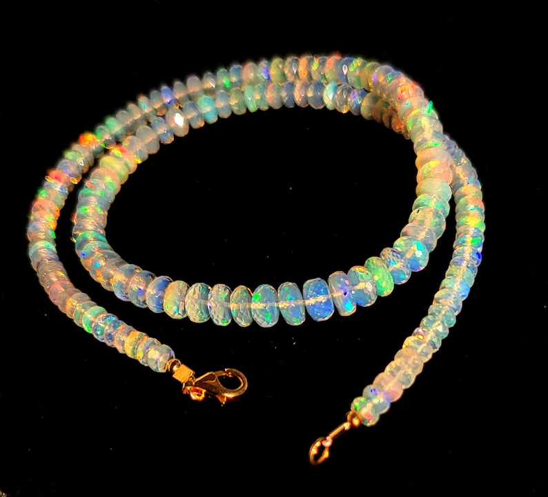 May include: A delicate necklace made of iridescent opal beads with a gold clasp. The necklace is layered and has a subtle shimmer.
