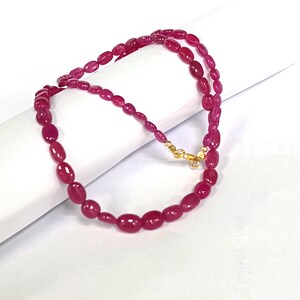 May include: A pink ruby gemstone bead necklace with a gold clasp.
