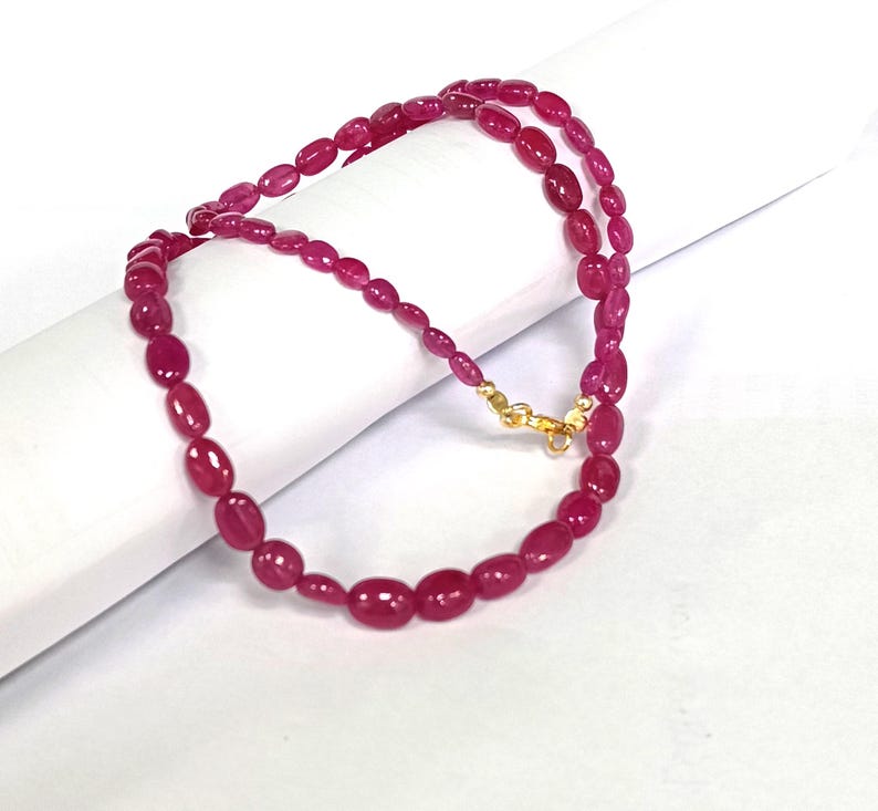 May include: A pink ruby gemstone bead necklace with a gold clasp.