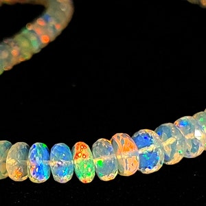May include: A strand of iridescent opal beads, each bead is a light milky white with flashes of rainbow colors. The beads are round and smooth.