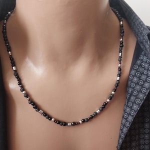 May include: A black beaded necklace with silver and red beads.