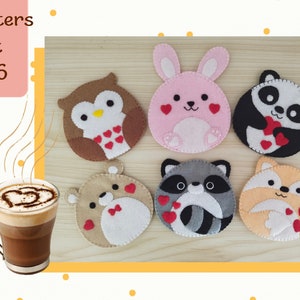 May include: Set of six felt coasters featuring cute animal designs. Each coaster has a different animal, including an owl, bunny, panda, raccoon, and fox. The coasters are decorated with red hearts and are perfect for adding a touch of whimsy to your home decor.