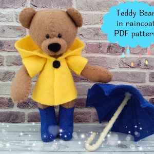 May include: A brown teddy bear wearing a yellow raincoat and blue rain boots holds a blue umbrella. The text "Teddy Bear in raincoat PDF pattern" is in a thought bubble above the bear.