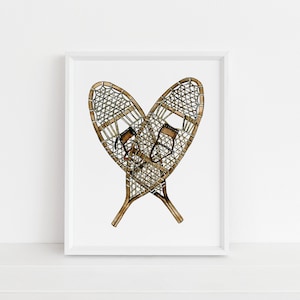 May include: A pair of brown wooden snowshoes with a woven design, crossed in a heart shape, on a white background.