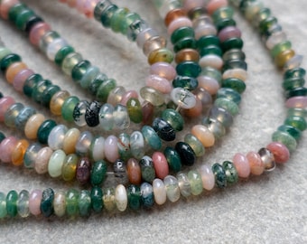 May include: Close-up of gemstone beads in shades of green, pink, and clear. The small, flat, round beads are strung together. The natural stone beads have a unique, organic appearance, suitable for jewellery making. The beads are measured in centimetres.