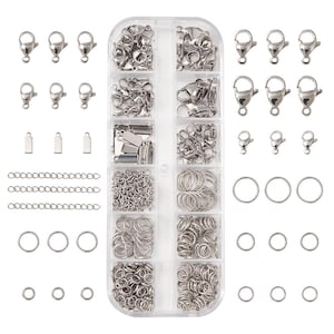 May include: A jewellery making kit featuring a clear plastic organiser box with twelve compartments filled with silver-toned metal findings, including lobster claw clasps, jump rings, crimp ends, and chain links, with loose pieces arranged around the box.