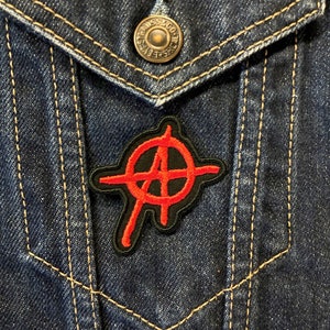 May include: A red anarchy symbol patch on a blue denim jacket.