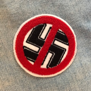 May include: A red circle with a white diagonal line through it. Inside the circle is a black and white swastika.