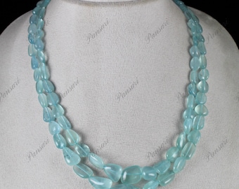 May include: A double strand necklace made of light blue aquamarine gemstone beads. The beads are faceted and have a teardrop shape.