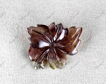 May include: A carved flower-shaped gemstone pendant with a brown and clear color scheme. The pendant is made of a translucent material with a sparkly finish.