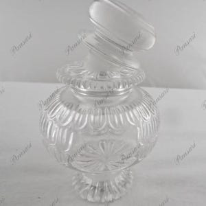 May include: A clear glass jar with a decorative, textured design. The jar has a lid with a unique, twisted shape.
