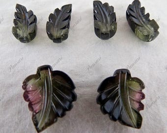 May include: Ten carved green and black leaf-shaped gemstone pendants. The pendants have a detailed carved design and are translucent.