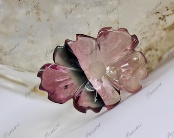 May include: A carved pink and black flower-shaped gemstone. The gemstone has a translucent appearance and intricate details.