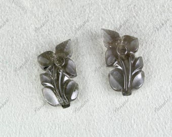 May include: Two gray carved flower-shaped pendants. The pendants are made of a translucent material and have a delicate floral design.
