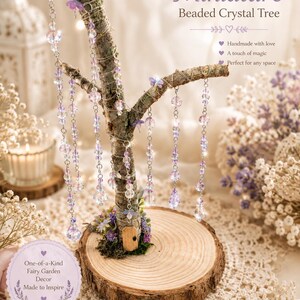 Puede incluir: Una escultura de &aacute;rbol en miniatura con una rama natural sobre una base de rodaja de madera. La rama est&aacute; decorada con alambre plateado y hebras colgantes de cuentas de cristal transparentes y moradas. Una peque&ntilde;a puerta de madera est&aacute; en la base.
