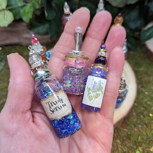 May include: Three small glass bottles with cork stoppers and glitter inside. The bottles have different labels: "Truth Serum", a floral design, and a pink and purple design.