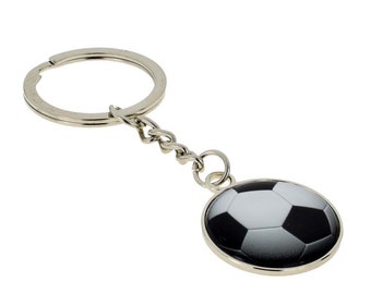 Puede incluir: Llavero plateado con un abalorio redondo de fútbol negro y blanco.