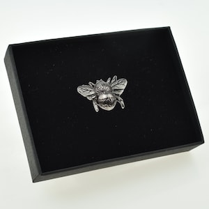 May include: A silver-toned pewter bumble bee brooch in a black velvet box.