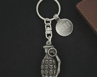 Llavero personalizado de peltre con calavera y granada, fabricado en Inglaterra, presentado en una bolsa de terciopelo.