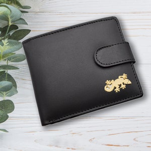 May include: Black leather wallet with a gold gecko design. The wallet has a flap closure and a single pocket.