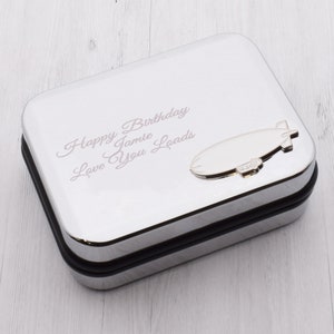 May include: A silver metal gift box with a small silver airship on the lid. The box is engraved with the text "Happy Birthday Jamie Loads Love You".