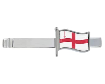 May include: A silver tie bar with a red cross on a white flag. The flag is attached to a silver stand.