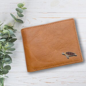 May include: A brown leather wallet with a sea turtle design embossed on the front.