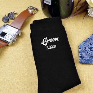 Puede incluir: Calcetines negros con bordado blanco que dice "Groom Adam".