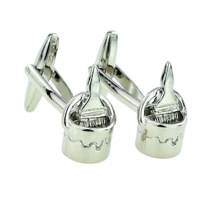 May include: A pair of silver cufflinks featuring a paint can with a paintbrush design.