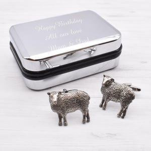 Könnte beinhalten: Silberne Manschettenknöpfe in Form von Schafen, mit einer silbernen Geschenkbox, die mit der Botschaft "Happy Birthday All our love Mum & Dad" graviert ist.