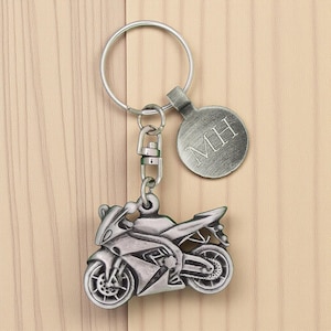 May include: Silver motorcycle keyring with a round tag engraved with "MH". The keyring features a detailed motorcycle charm and a split ring for keys. The motorcycle charm is approximately 3.8 cm long.