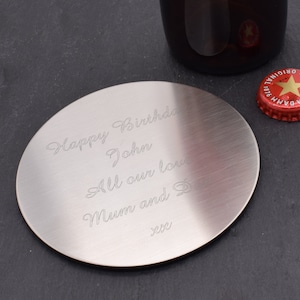 May include: A silver round coaster with an engraved message that reads "Happy Birthday John All our love Mum and Dad xxx".