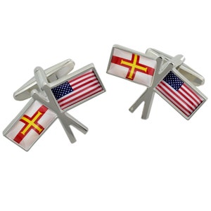 May include: A pair of silver cufflinks with crossed flags. One flag is the American flag and the other is the flag of Jersey.