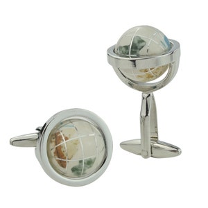 Peut inclure: Une paire de boutons de manchette en argent avec un motif de globe terrestre. Les globes sont blancs avec des continents bruns et verts. Les boutons de manchette ont un motif de globe pivotant.