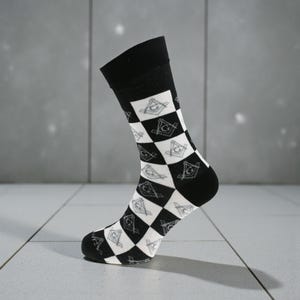 Könnte beinhalten: Schwarz-weiß gemusterte Socke. Die Socke hat ein Schachbrettmuster mit abwechselnd schwarzen und weißen Quadraten. Jedes weiße Quadrat enthält ein graues Freimaurersymbol. Der obere Teil und die Ferse sind schwarz.