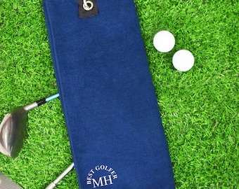 May include: A navy blue golf towel with a white embroidered circle that says "Best Golfer by Par" and the initials "MH".