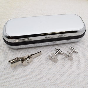 May include: Silver cufflinks and tie clip set in a silver case. The cufflinks and tie clip feature a propeller design. The case is engraved with the text "Happy Birthday All our love Mum & Dad".