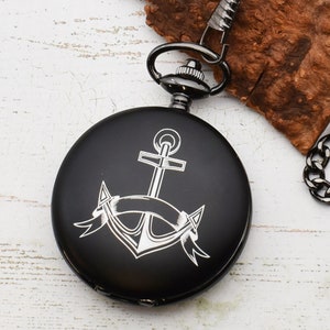 Może przedstawiać: Czarny zegarek kieszonkowy z srebrnym wzorem kotwicy i wstążki.