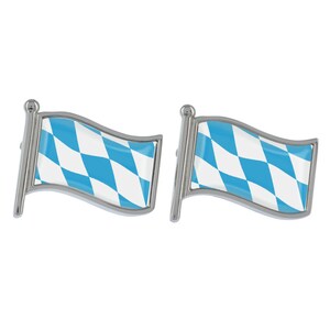 May include: A pair of silver cufflinks featuring a blue and white Bavarian flag design. The flags are waving in the wind.