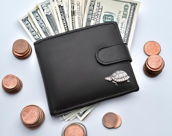 May include: A black leather wallet with a silver turtle charm, a stack of US dollar bills, and a pile of copper coins.