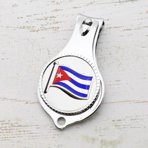 May include: Silver nail clippers with a circular design featuring the Cuban flag. The flag is red, white and blue with a single white star in the top left corner.