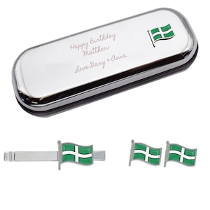 Pode incluir: Uma caixa de presente prateada com um design de bandeira verde e branca. A caixa é gravada com o texto "Happy Birthday Matthew Love Harry & Anna". A caixa vem com uma gravata combinando e botões de punho.