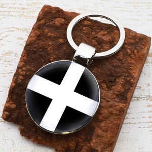 May include: A silver keychain with a black and white circular charm featuring a white cross on a black background.