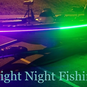 Puede incluir: Un barco de pesca negro con una tira de luz LED verde y morada que recorre el lateral. El barco est&aacute; en un remolque y el texto "Bright Night Fishing" es visible en la parte inferior central de la imagen.